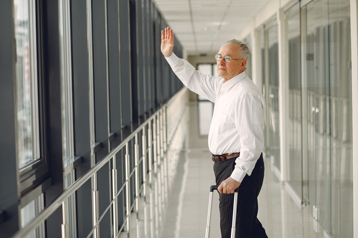 An older man pulling a rolling suitcase through an airport terminal, the kind of winter trip that raises the question of how Medicare covers a Delta County resident in another state